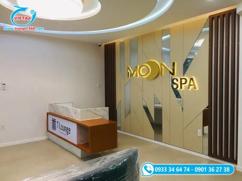 Vách logo spa cao cấp với chữ nổi inox vàng hắt sáng trên nền trang trí hiện đại