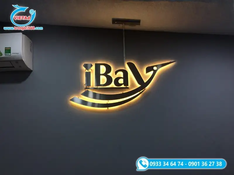 Logo công ty chữ inox hắt sáng LED gắn trên tường tối màu, tạo hiệu ứng ánh sáng nổi bật